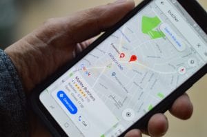 Man holding smartphone displaying a map; image by Henry Perks, via Unsplash.com.