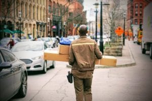 UPS employee in uniform carrying packages; image by Maarten van den Heuvel, via unsplash.com.