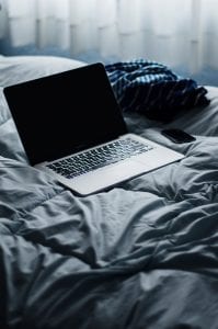 Laptop and smartphone on bed; image by Martin Castro, via Unsplash.com.
