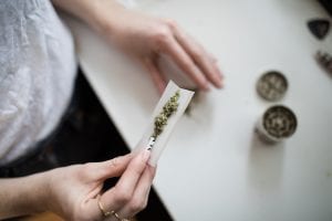 Woman rolling a marijuana joint; image by Thought Catalog, via unsplash.com.