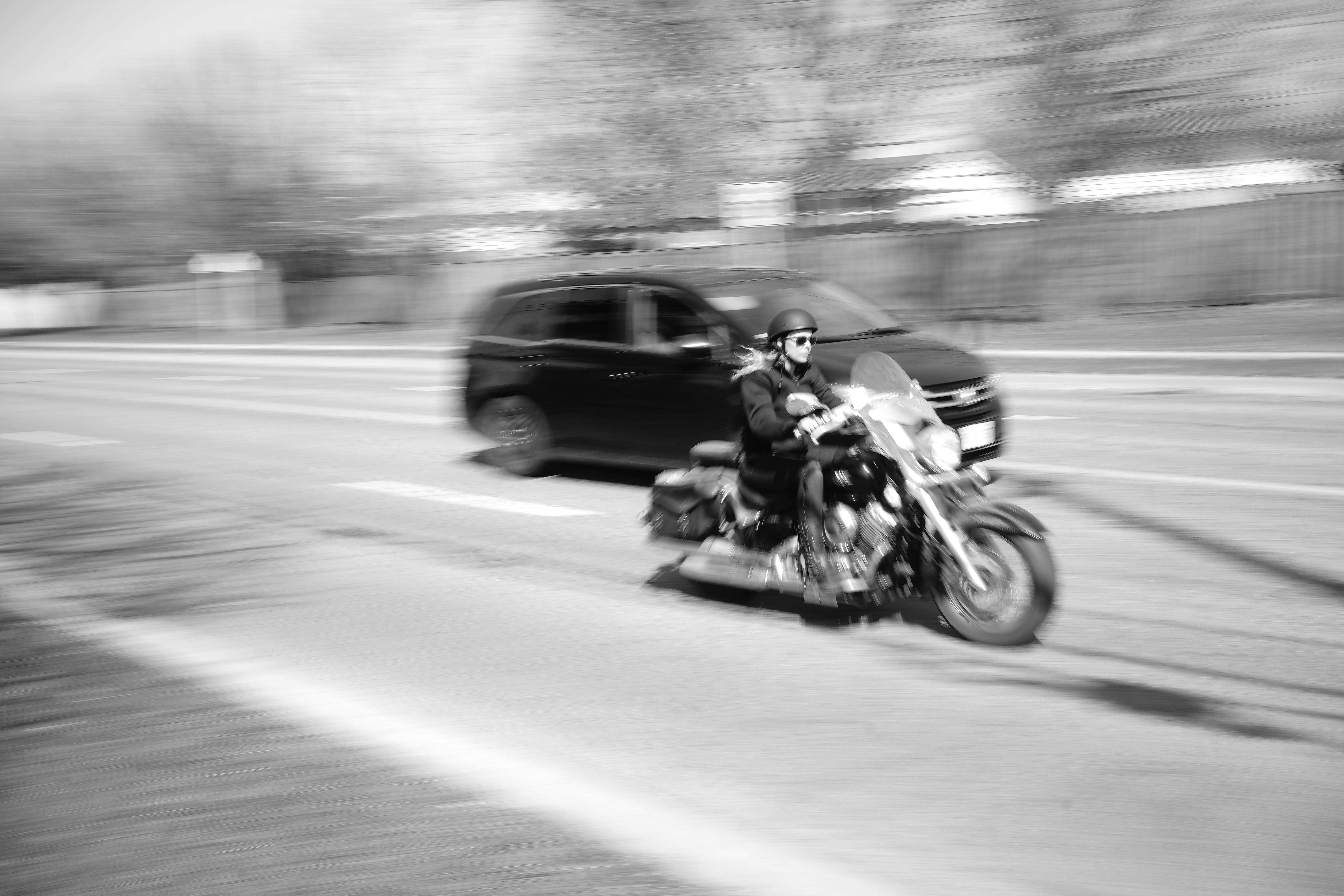 Man riding a motorcycle next to a minivan on the highway; image by VanveenJF, via unsplash.com.