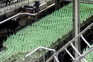 Glass bottles on conveyor belt; image by Waldemar Brandt, via Unsplash.com.