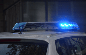 Roof of police car with blue light lit; image by Pixabay, via Pexels.com.