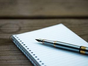 Fountain pen on spiral notebook; image by Aaron Burden, via Unsplash.com.