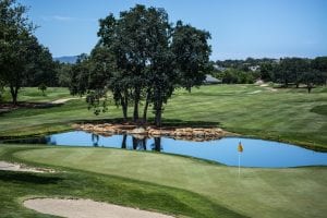 Golf course with pond, yellow flag marking hole; image by Edewaa Foster, via Unsplash.com.