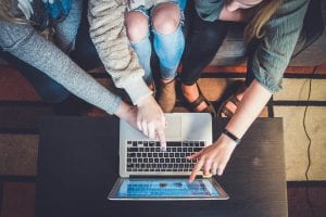 Three women pointing at laptop screen; image by John Schnobrich, via Unsplash.com.