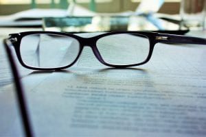 Reading glasses on paper; image by Mari Helin, via Unsplash.com.