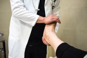 Doctor examining woman’s foot; image by Marlon Lara, via Unsplash.com.