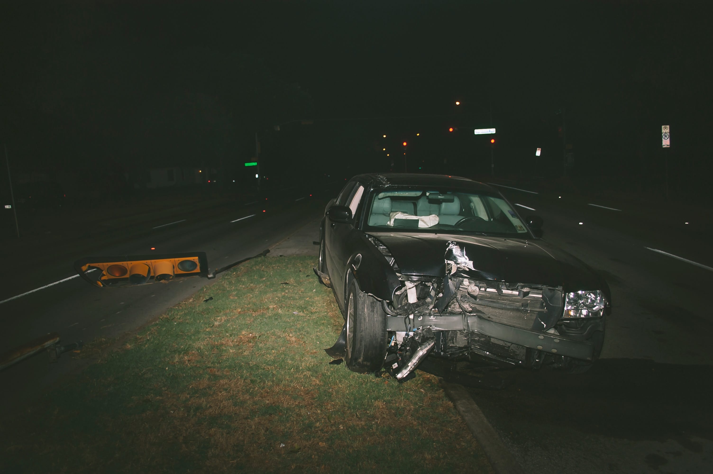 A car with serious front-end damage in the street at night next to a fallen traffic light; image by Matthew T. Rader, via Unsplash.com.