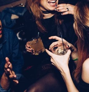 Two women talking while holding drinks; image by Michael Discenza, via Unsplash.com.