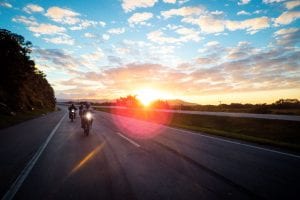 Three motorcyclists riding on an open road at sunset; image by Rafael Lopes de Lima, via Unsplash.com.