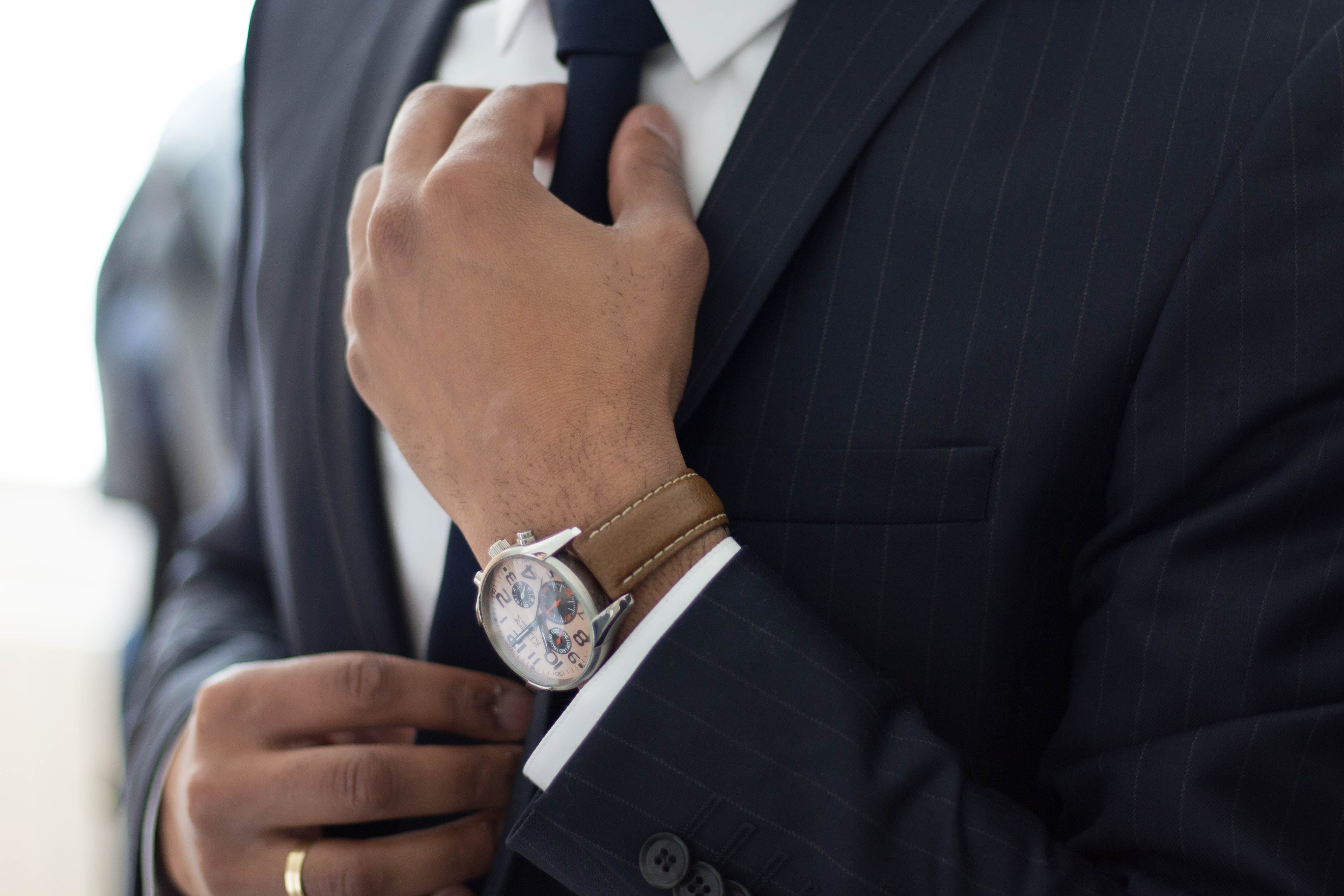 Man wearing watch with black suit; image by Ruthson Zimmerman, via Unsplash.com.