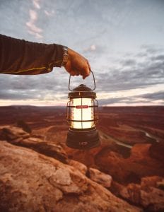 Person holding a camping lantern at dusk; image by Matthew Brodeur, via Unsplash.com.