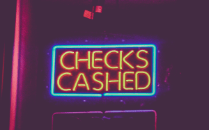 Neon “Checks cashed” sign; image by Tony Webster from Oakland, California, CC BY 2.0, no changes.