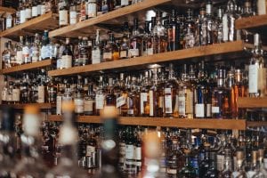 Assorted bottles of alcohol on a shelf; image by Adam Wilson, via Unsplash.com.