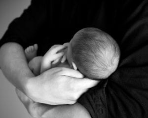 Person holding newborn baby; image by Pixabay, via Pexels.com.