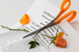 Marriage certificate with orange rose, both being cut in two by orange-handled scissors; image by Stevepb, via Pixabay.com.