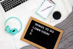 White desk with computer keyboard, coffee mug, turquoise headphones and clipboard, and a to-do list with “Own today” as the number one item. Image by Emma Matthews, via Unsplash.com.
