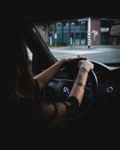 Woman in BMW with hands on the steering wheel; image by Gijs Coolen, via Unsplash.com.