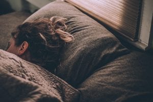 Woman sleeping on brown bed linens; image by Gregory Pappas, via Unsplash.com.