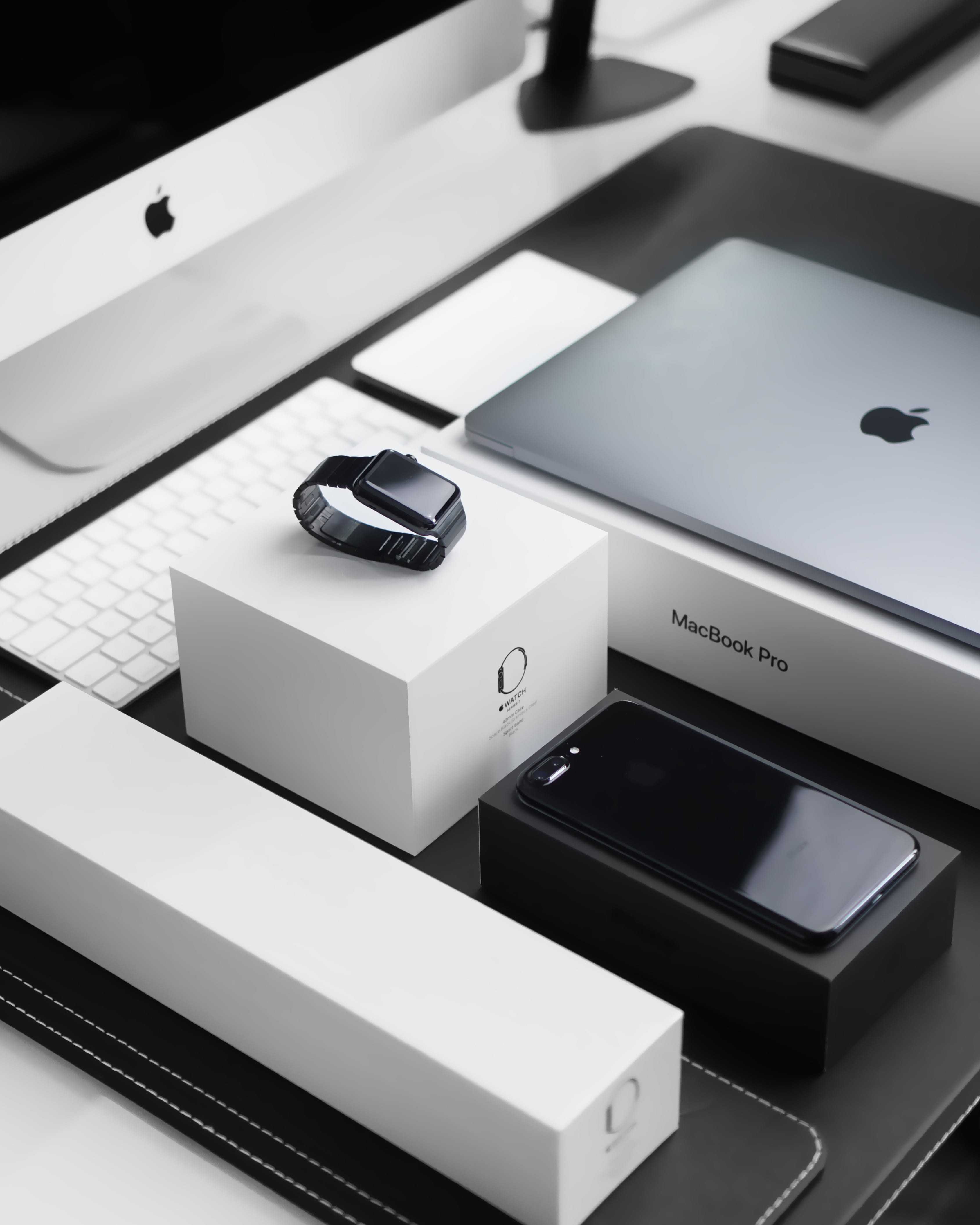Space black case Apple Watch, silver MacBook Pro, jet black iPhone 7 Plus, and silver iMac with corresponding boxes; image by Julian O’Hayon, via Unsplash.com.