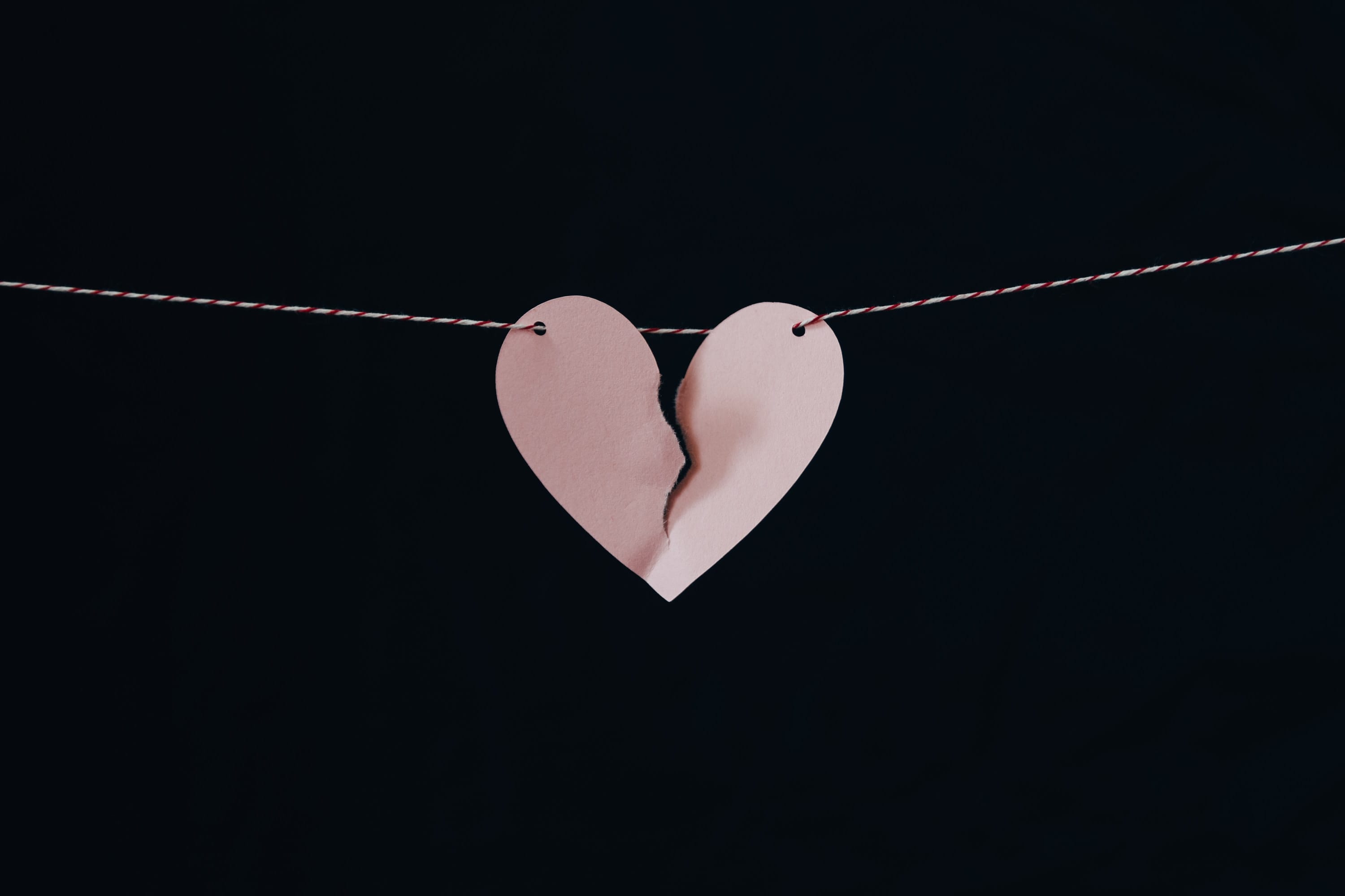 Pink heart on a string, heart torn down the middle; image by Kelly Sikkema, via Unsplash.com.