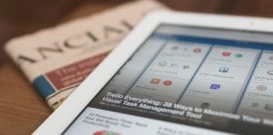 Tablet sitting on top of financial section of newspaper; image by Matthew Guay, via Unsplash.com.