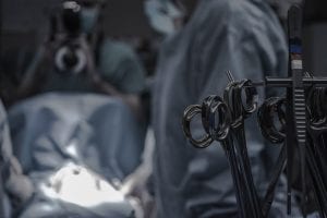 Gray surgical scissors near doctors in operating room; image by Piron Guillaume, via Unsplash.com.