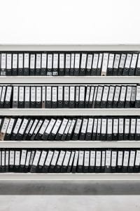 A shelf of binders full of paperwork; image by Samuel Zeller, via Unsplash.com.