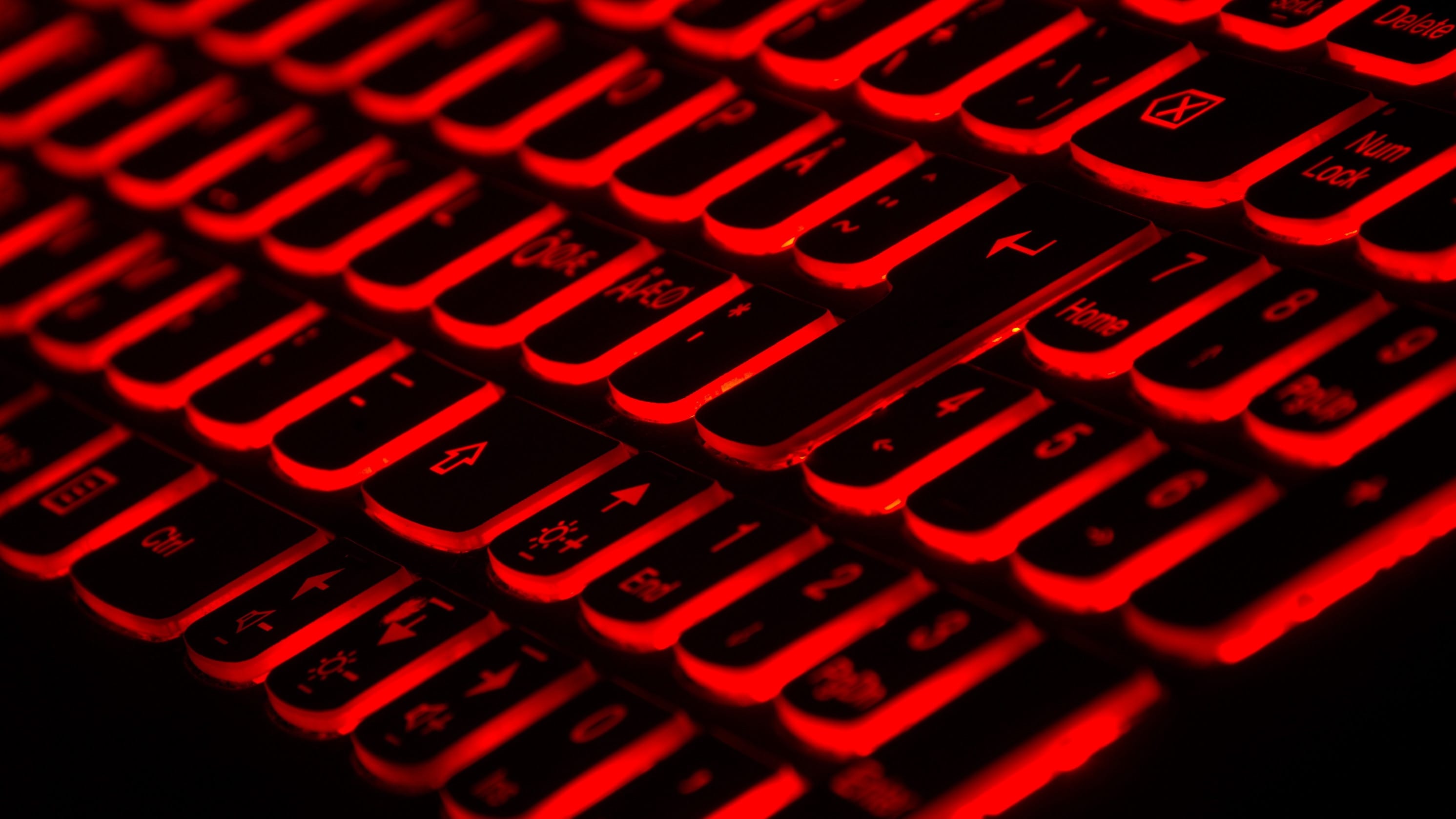 Computer keyboard with black keys backlit in red; image by Taskin Ashiq, via Unsplash.com.