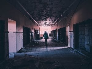 Person walking in darkened hallway; image by Andrew Amistad, via Unsplash.com.