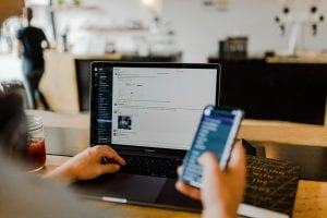 Man using computer and smartphone; image by Austin Distel, via Unsplash.com.