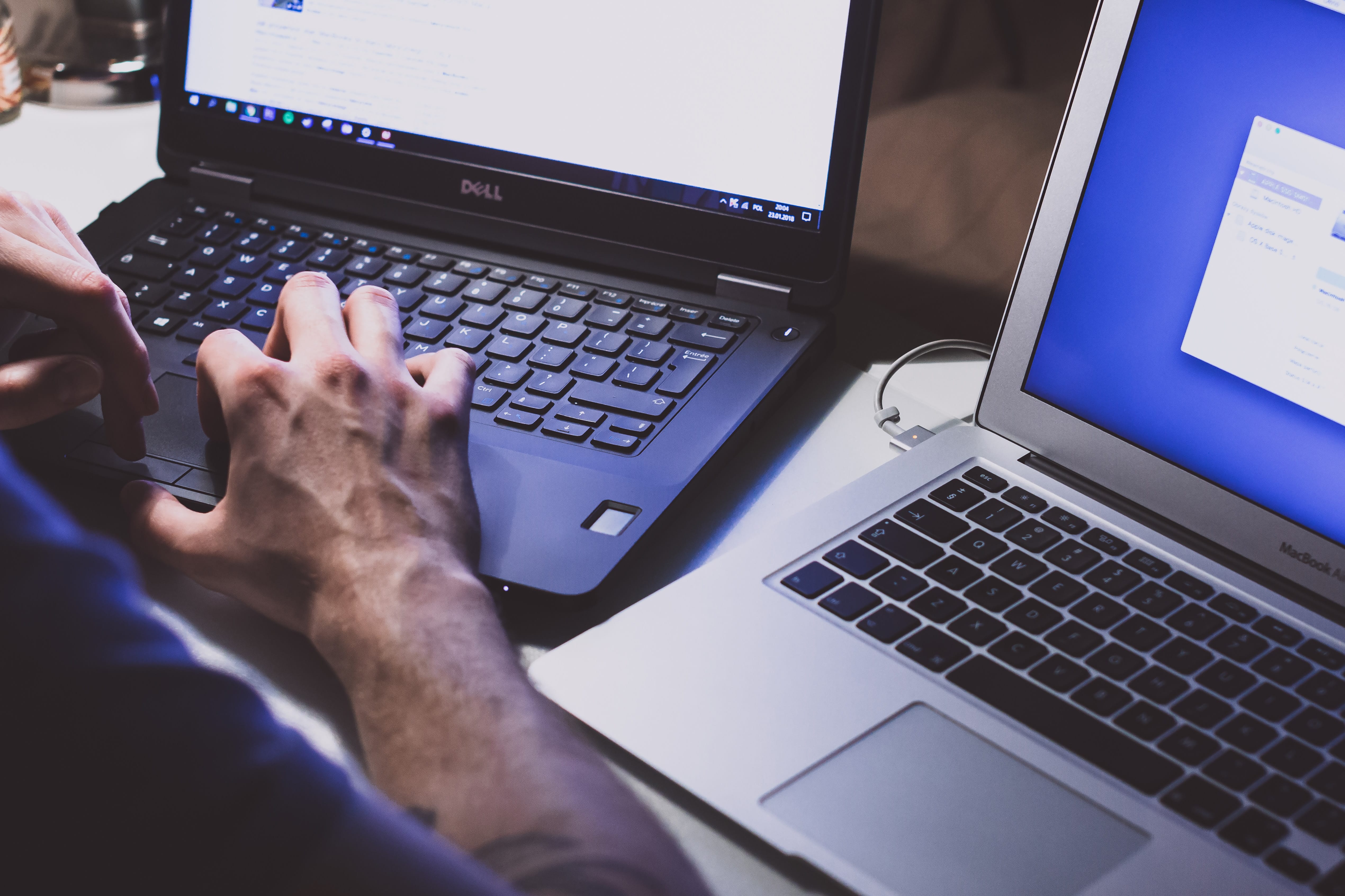 Man using two laptops; image by freestocks.org, via Unsplash.com.