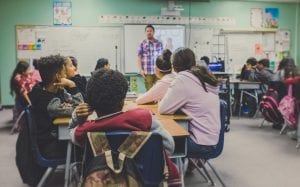 Classroom with teacher at front; image by NeONBRAND, via Unsplash.com.