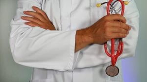 Male doctor in white coat with red stethoscope; image by Online Marketing, via Unsplash.com.