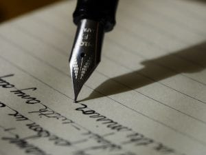 Fountain pen on black lined paper; image by Aaron Burden, via Unsplash.com.