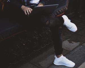 Man in black jeans with legs crossed using laptop; image by Alexandra K, via Unsplash.com.