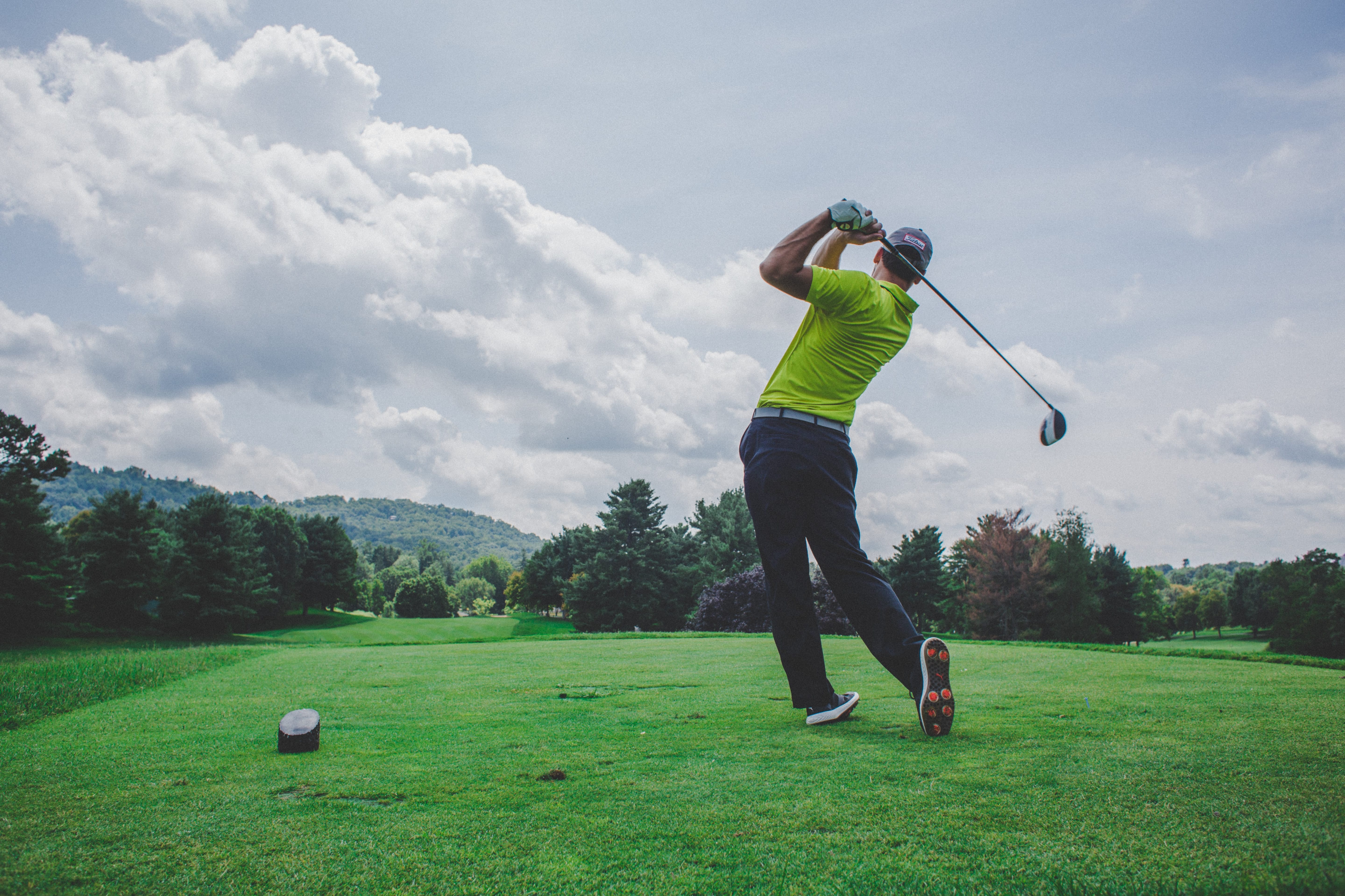 Man hitting golf ball on course; image by Court Cook, via Unsplash.com.