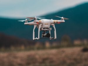 Selective focus shot of white and gold airborne drone; image by Jared Brashier, via Unsplash.com.