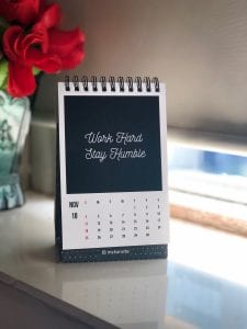 2019 calendar on white table. Print says “Work Hard, Stay Humble.” Image by Manasvita S, via Unsplash.com.