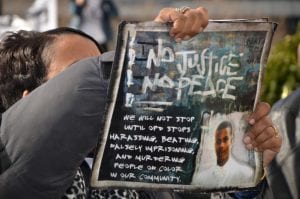 A woman holds a sign protesting police brutality.