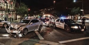 Tow truck picking up silver car after head-on collision, police car off to the side; image by Chris Yarzab, via Flickr, CC BY 2.0, no changes.