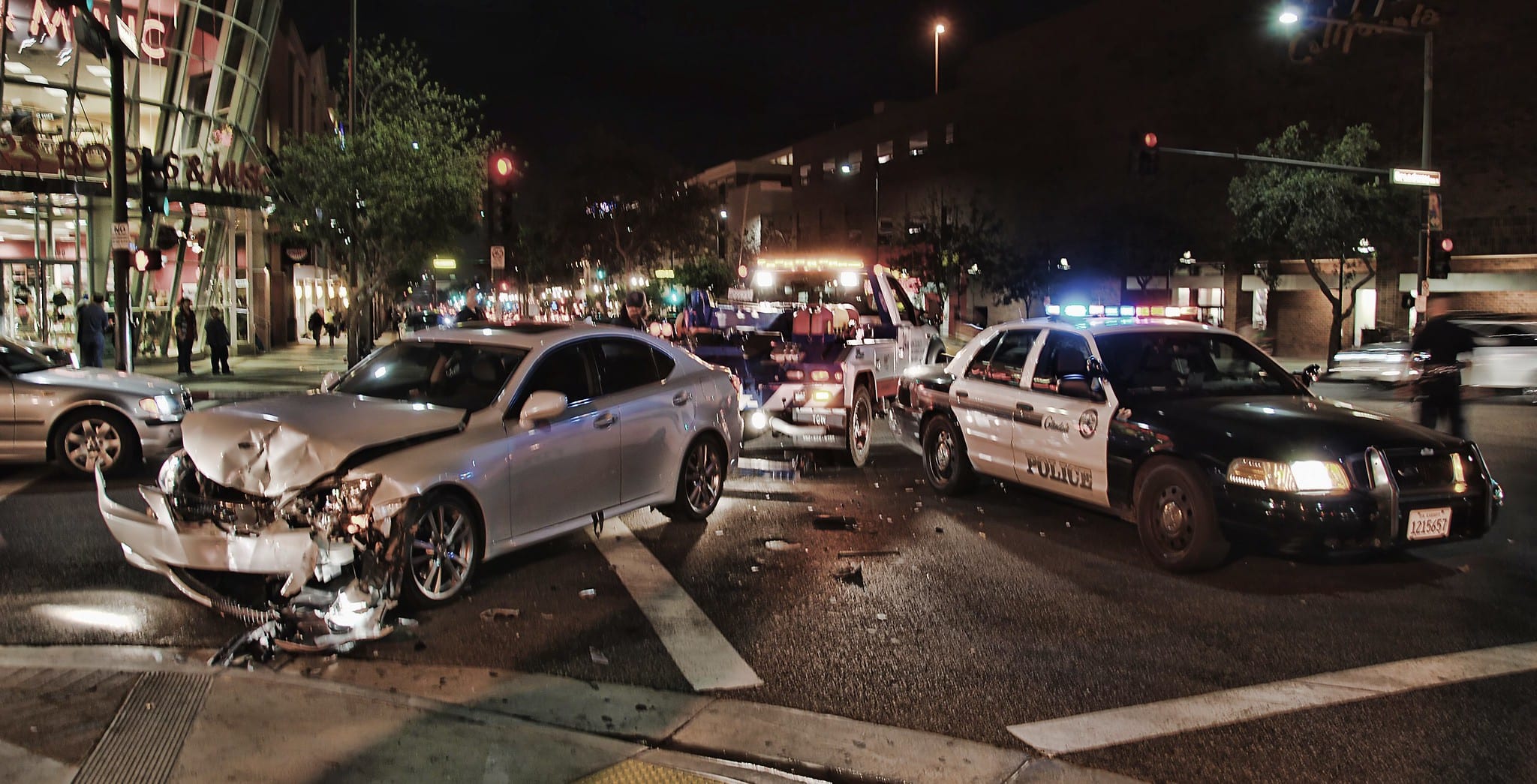 Tow truck picking up silver car after head-on collision, police car off to the side; image by Chris Yarzab, via Flickr, CC BY 2.0, no changes.