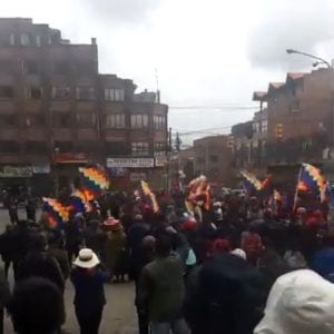 A gathering of people on a city street holding aloft colorful flags.