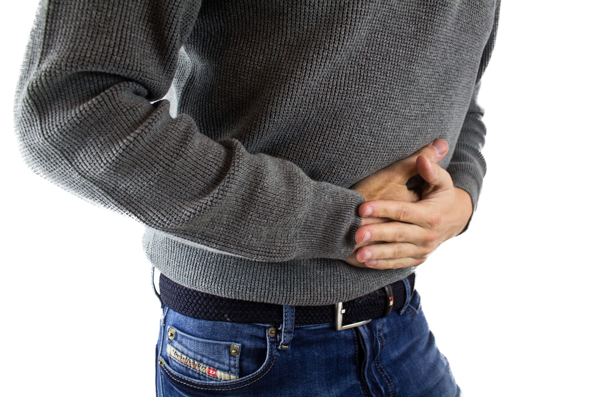 Man in blue jeans and grey sweater holding abdomen in pain; image by derneuemann, via Pixabay.com.