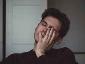 Man wearing black turtleneck, eyes closed, hand on face; image by Adrian Swancar, via Unsplash.com.