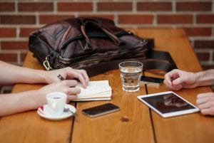 Two people meeting with iphone and ipad; image by Alejandro Escamilla, via Unsplash.com.