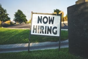 Now Hiring sign on lawn; image by Free To Use Sounds, via Unsplash.com.