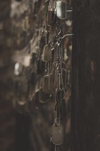 Silver-colored dog tags hanging on hooks shallow focus photography; image by Holly Mindrup, via Unsplash.com.