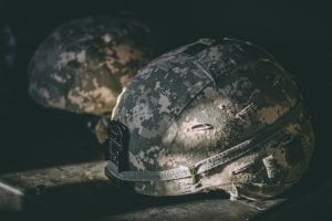 Gray and brown camouflage nutshell helmet on table; image by Israel Palacio, via Unsplash.com.